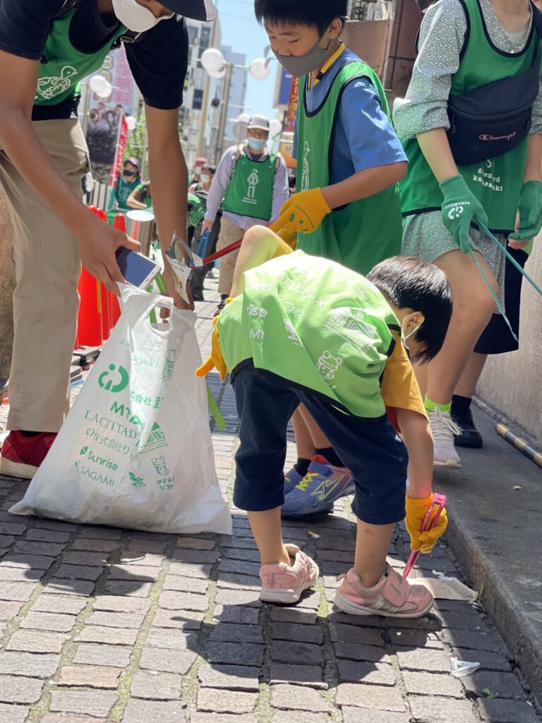 子供達が街でゴミ拾いをしている写真。